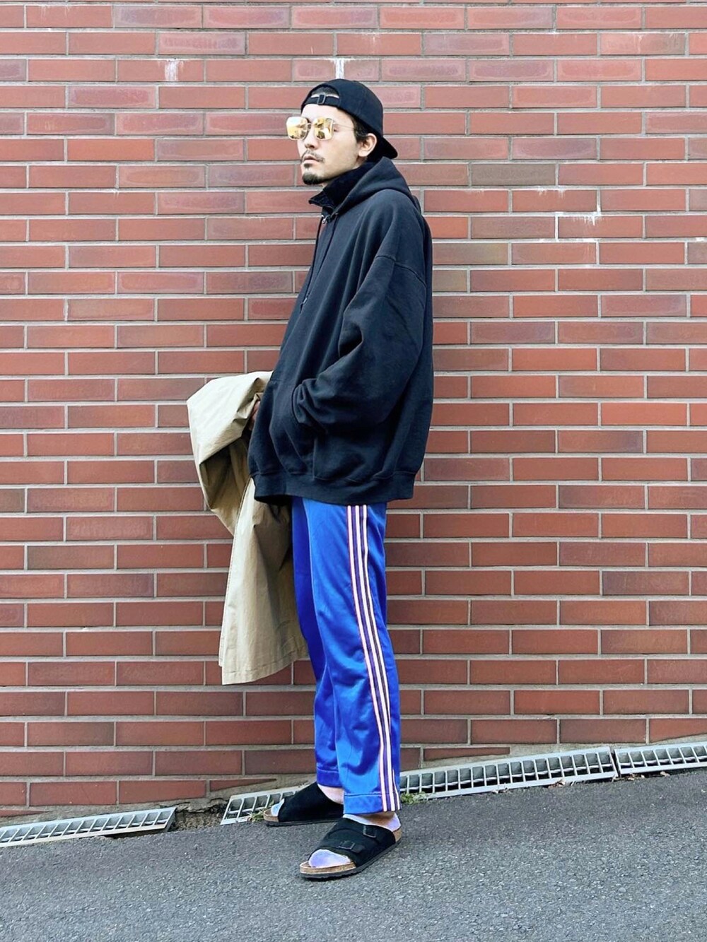 ベージュ系のステンカラーコート、ブラック系のパーカー、ブラック系のその他アウターを着用したメンズの秋コーディネートの2枚目の写真