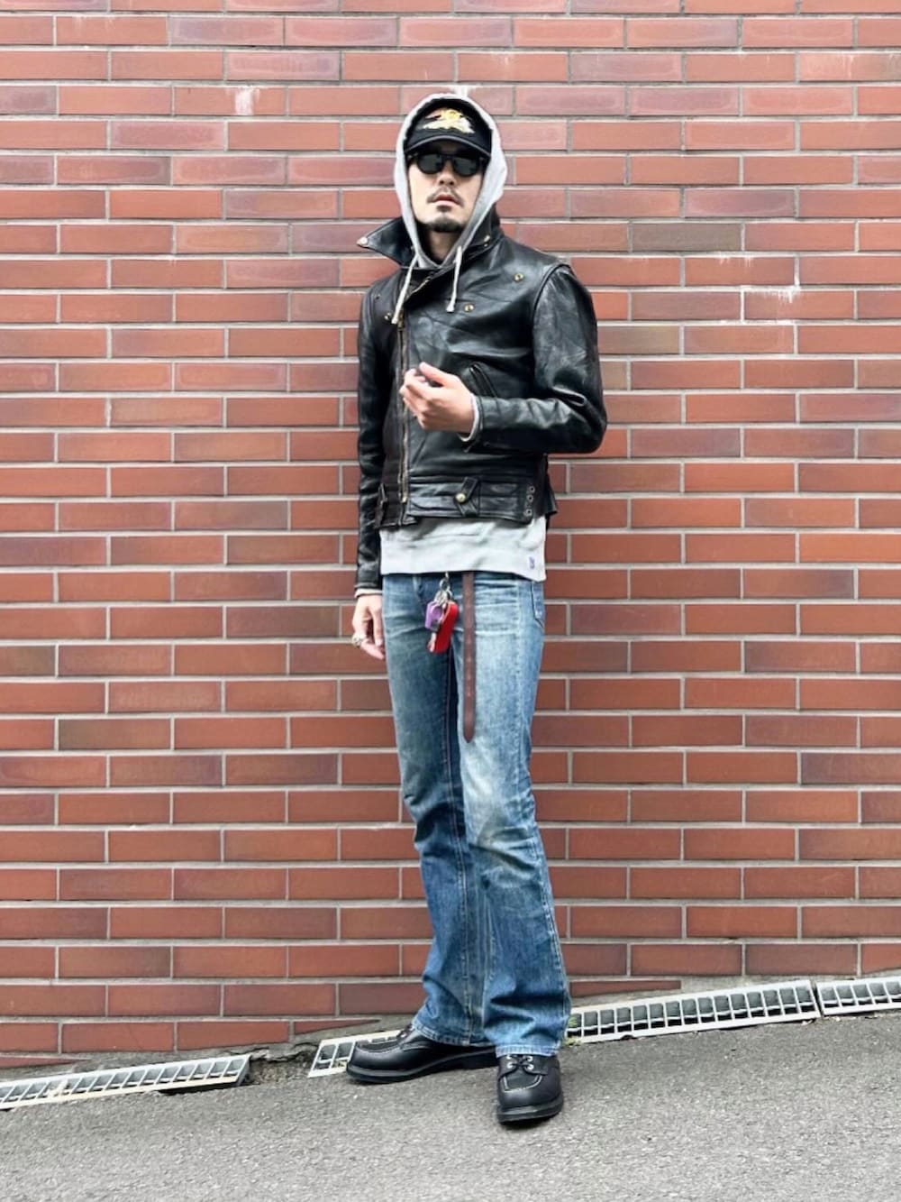 ブラック系のライダースジャケット、グレー系のパーカー、ブルー系のデニムパンツを着用したメンズの春コーディネートの3枚目の写真