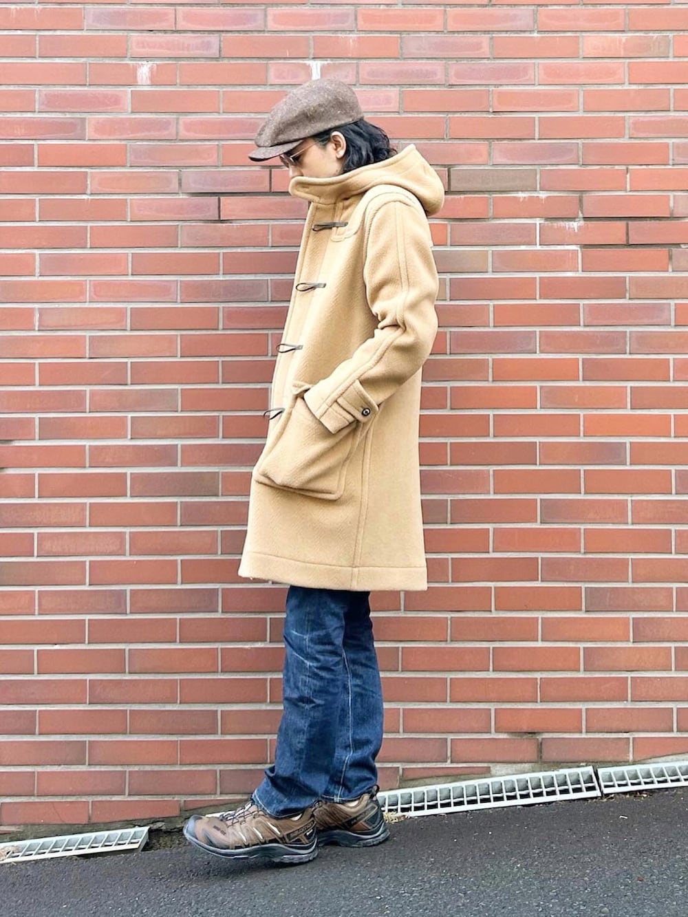 ベージュ系のダッフルコート、ブラック系のニット/セーター、ブルー系のデニムパンツを着用したメンズの冬コーディネートの2枚目の写真