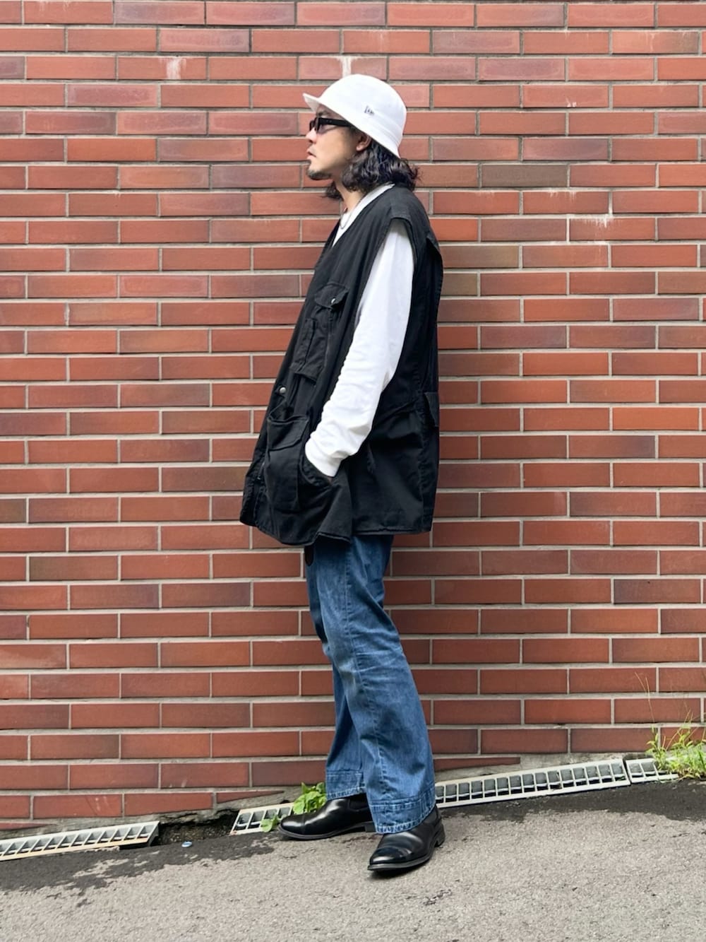ブラック系のブーツ、ブラック系のベスト、ホワイト系のTシャツ/カットソーを着用したメンズの秋コーディネートの2枚目の写真