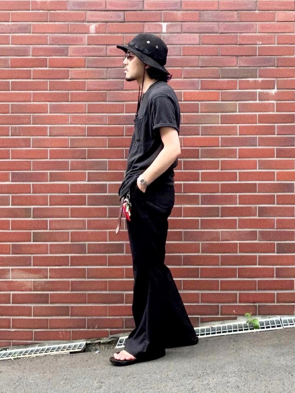 グレー系のタンクトップ、ブラック系のスラックス、ブラック系のサンダルを着用したメンズの夏コーディネートの2枚目の写真