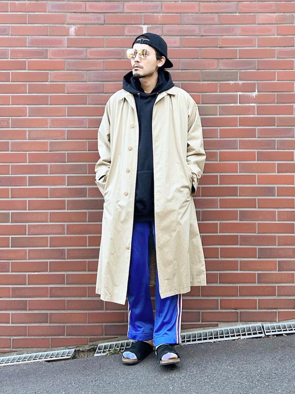 ベージュ系のステンカラーコート、ブラック系のパーカー、ブラック系のその他アウターを着用したメンズの秋コーディネートの3枚目の写真