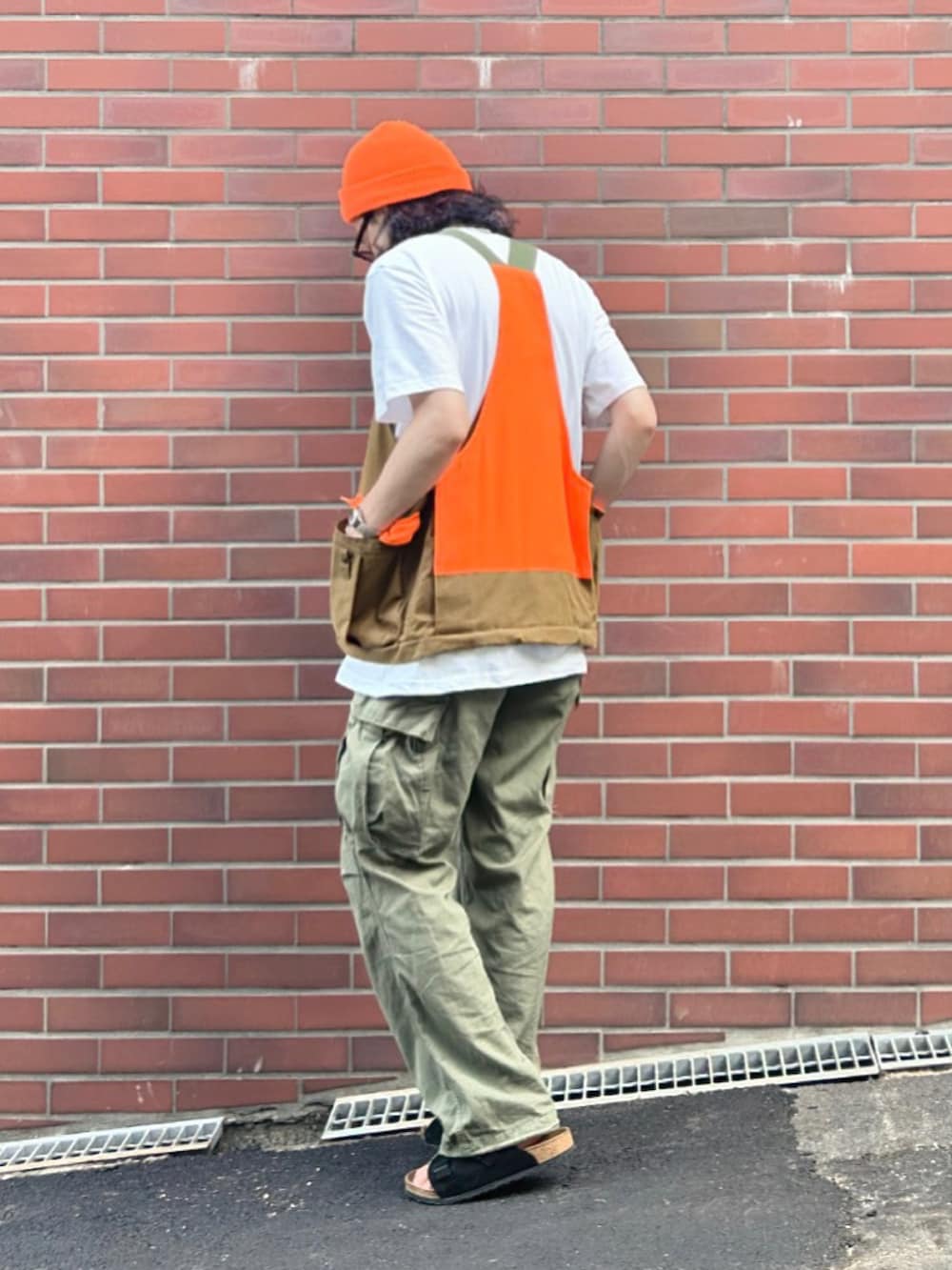 グリーン系のベスト、ホワイト系のTシャツ/カットソー、グリーン系のカーゴパンツを着用したメンズの夏コーディネートの2枚目の写真