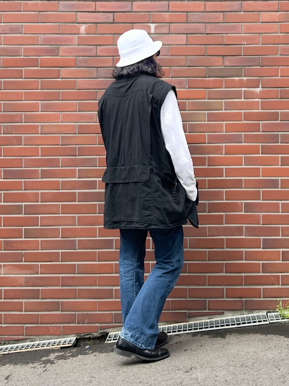 ブラック系のブーツ、ブラック系のベスト、ホワイト系のTシャツ/カットソーを着用したメンズの秋コーディネートの3枚目の写真
