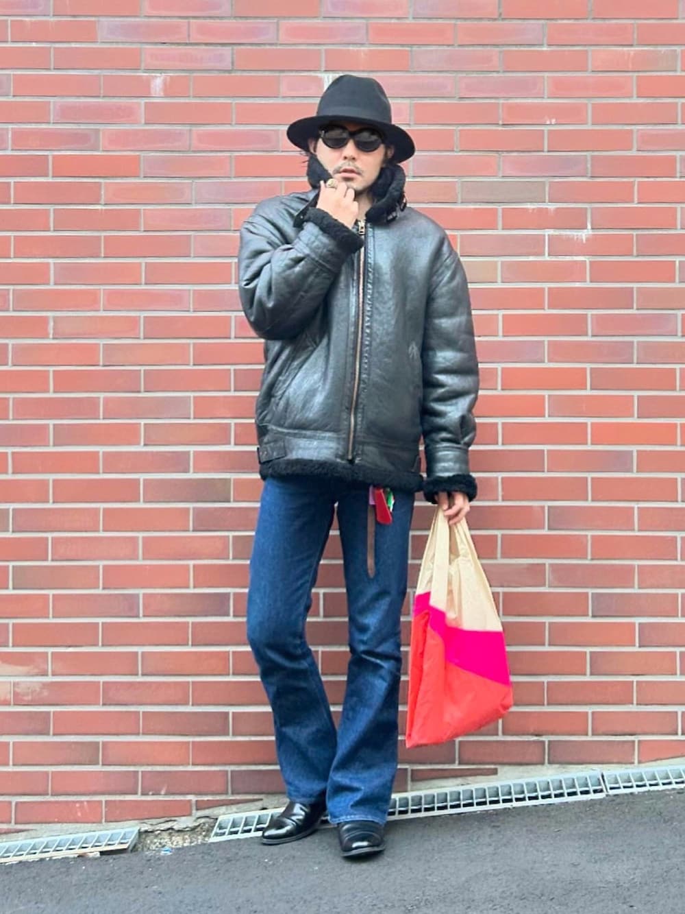 ブラック系のムートンコート、グレー系のニット/セーター、ホワイト系のTシャツ/カットソーを着用したメンズの冬コーディネートの2枚目の写真