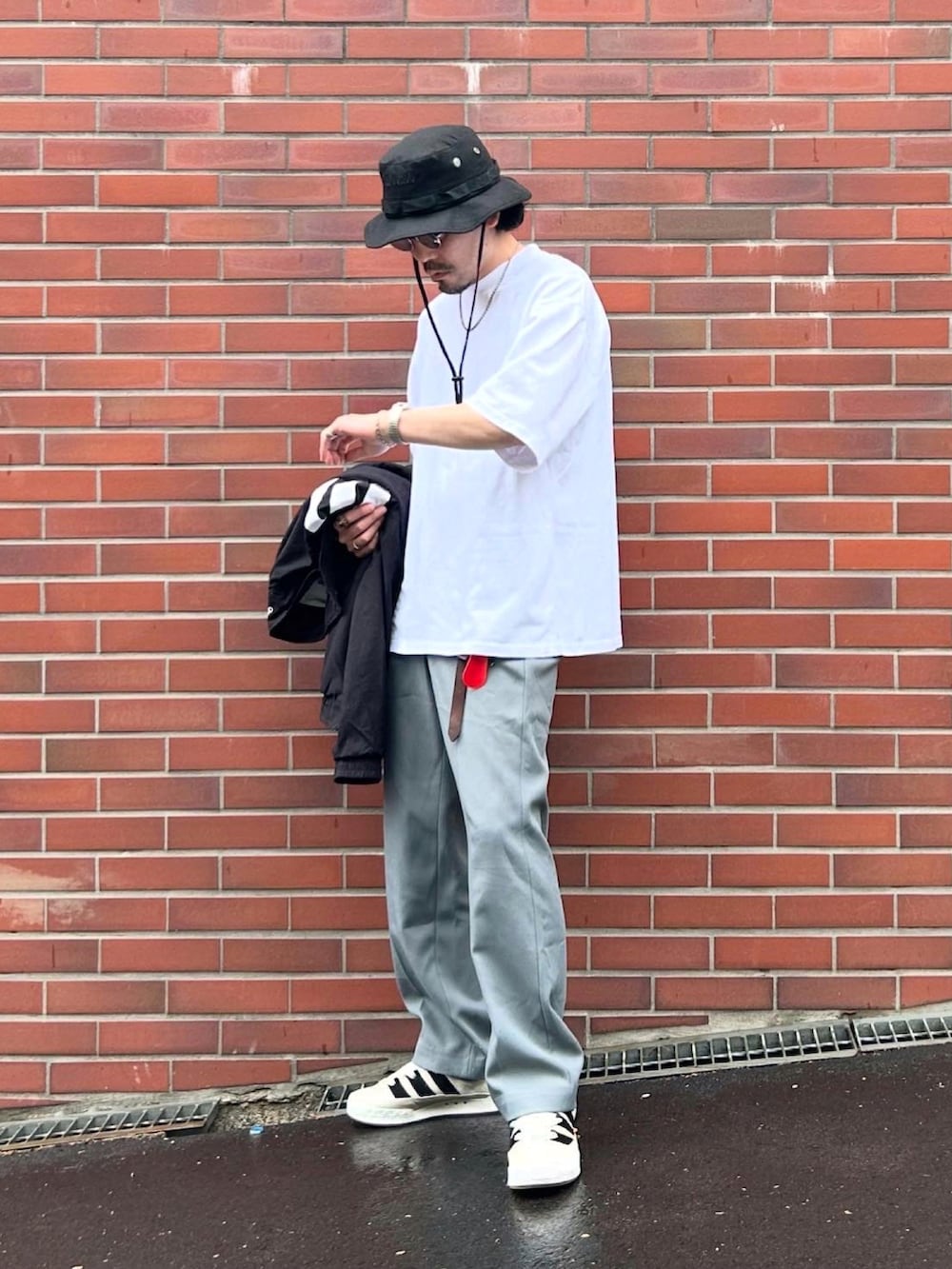 ブラック系のナイロンジャケット、ホワイト系のTシャツ/カットソー、グレー系のスラックスを着用したメンズの春コーディネートの2枚目の写真