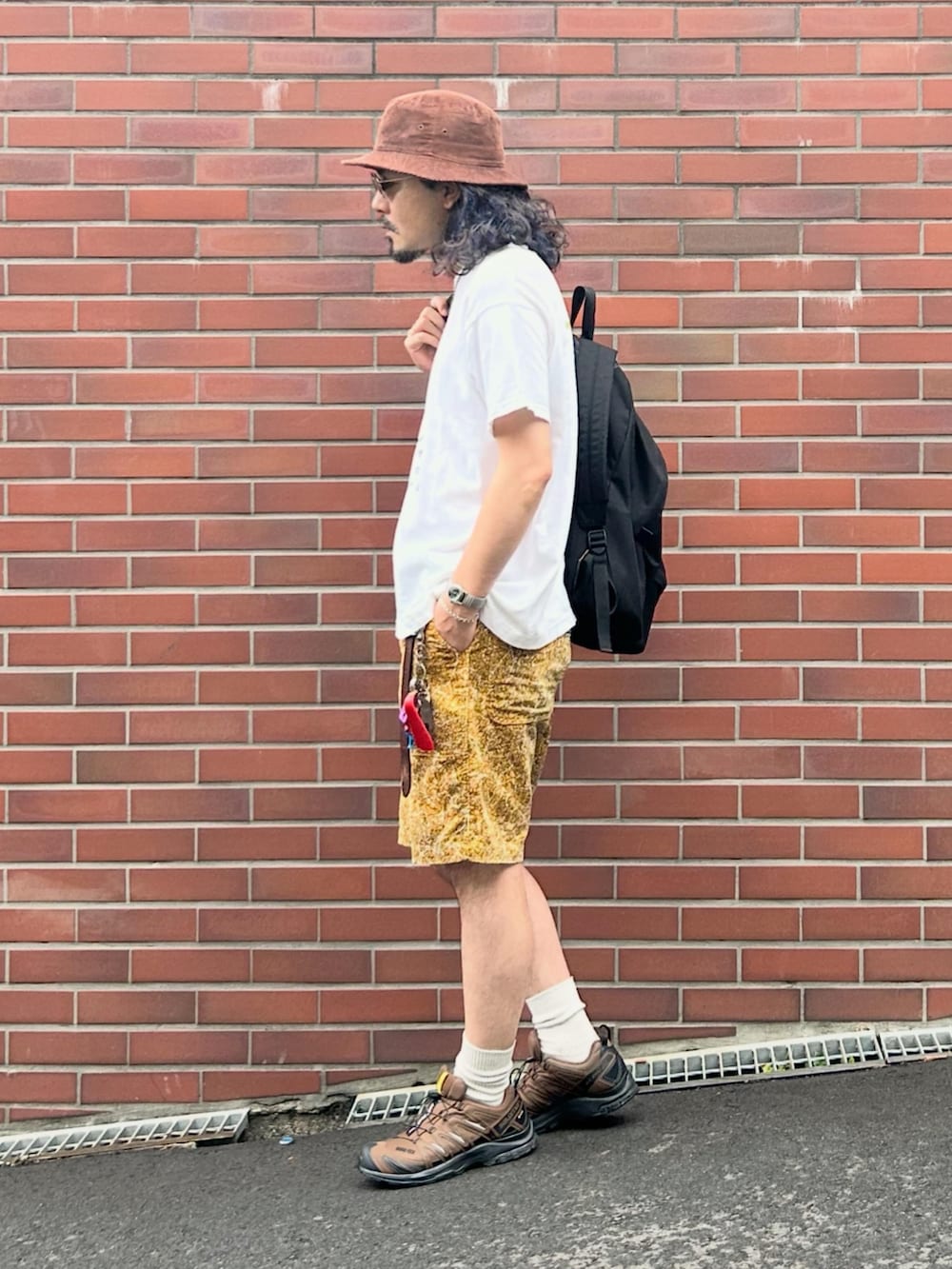 ブラウン系のスニーカー、ホワイト系のTシャツ/カットソー、イエロー系のパンツを着用したメンズの夏コーディネートの2枚目の写真