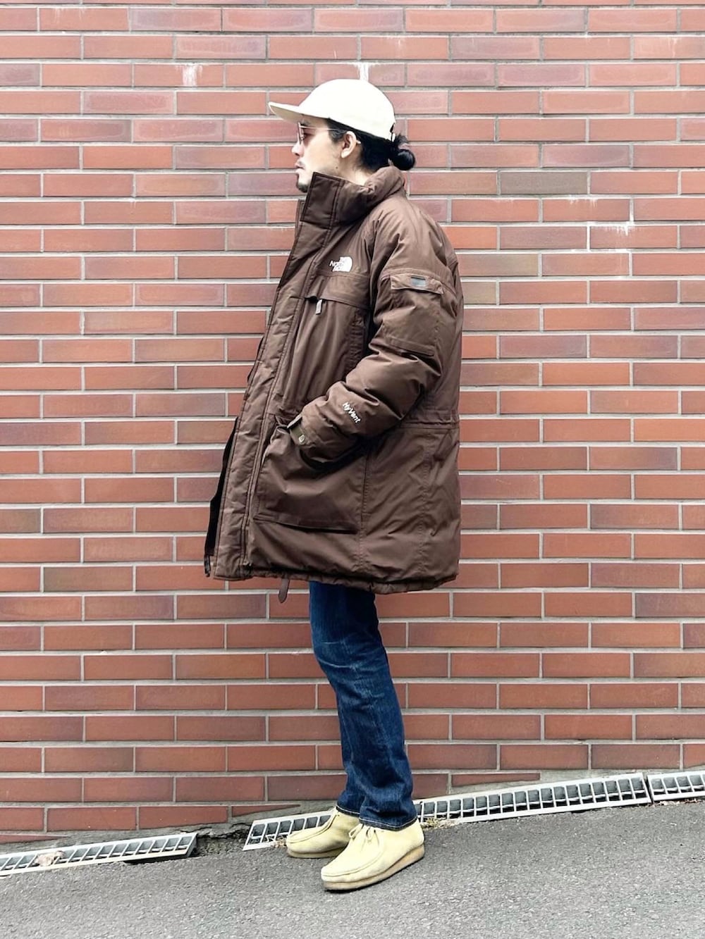 ブラウン系のダウンジャケット/コート、グレー系のスウェット、ブルー系のデニムパンツを着用したメンズの冬コーディネートの2枚目の写真