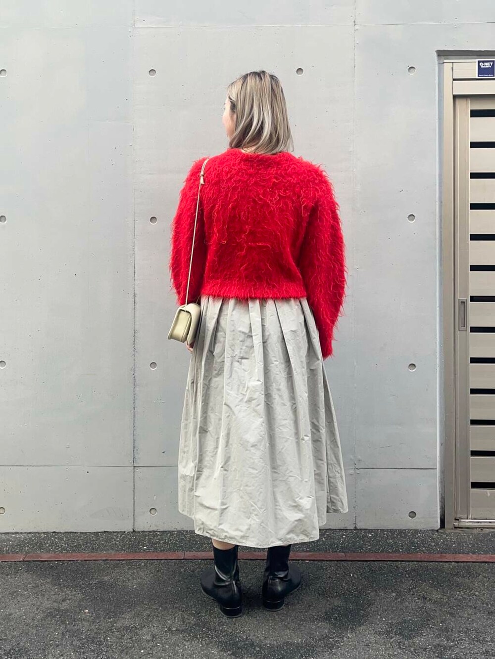 レッド系のカーディガン/ボレロ、ホワイト系のショルダーバッグ、グリーン系のスカートを着用したレディースの冬コーディネートの3枚目の写真