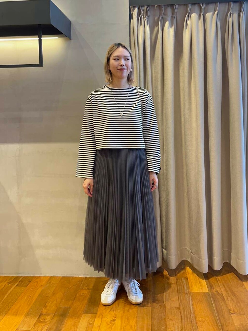 ブラック系のショルダーバッグ、グレー系のスカート、ホワイト系のTシャツ/カットソーを着用したレディースの夏コーディネートの3枚目の写真