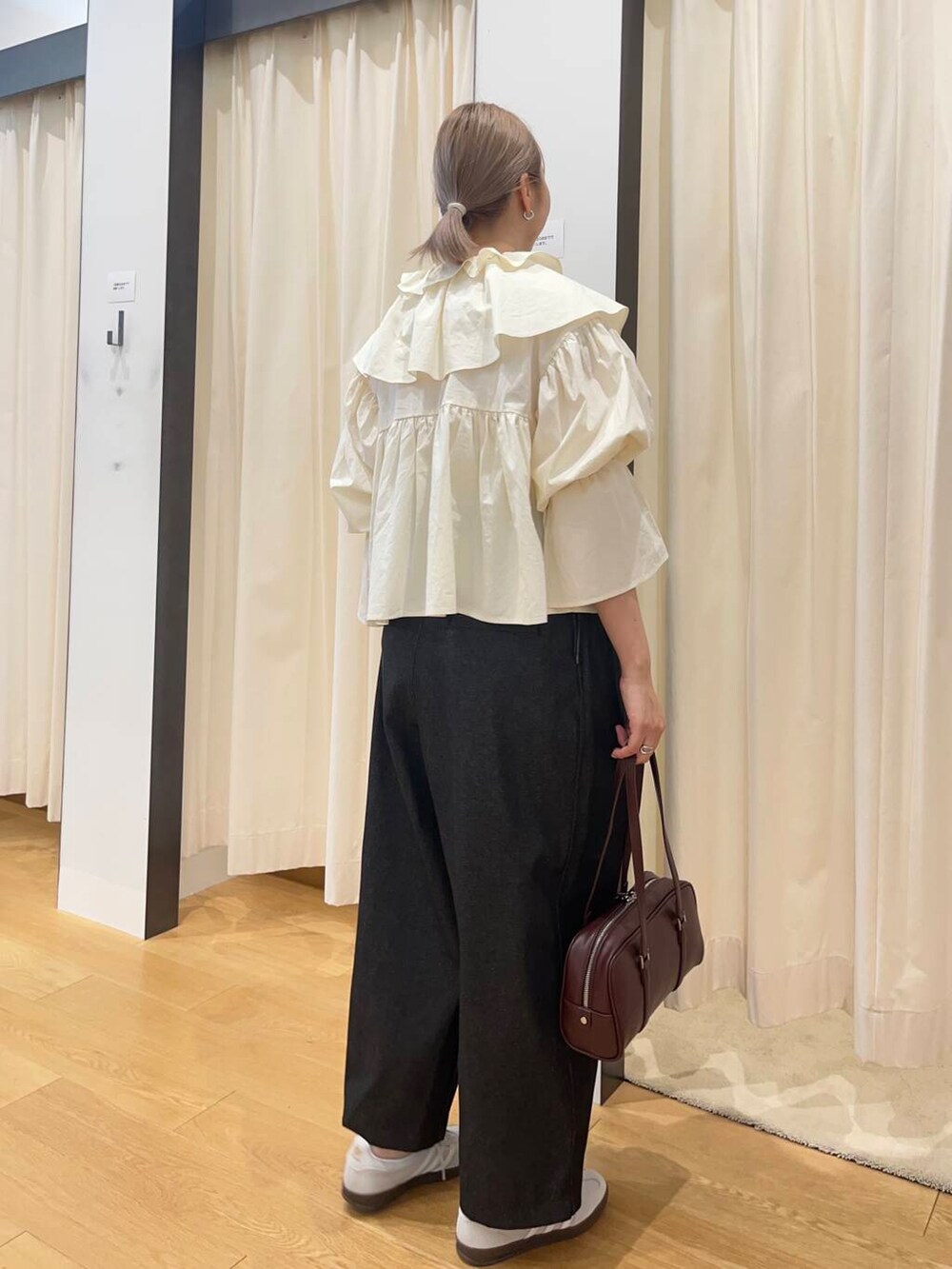 ブラック系のデニムパンツ、グレー系のスニーカー、ホワイト系のシャツ/ブラウスを着用したレディースの秋コーディネートの2枚目の写真