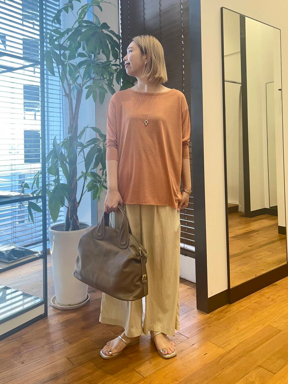 ベージュ系のその他パンツ、オレンジ系のTシャツ/カットソー、ベージュ系のボストンバッグを着用したレディースの夏コーディネートの2枚目の写真