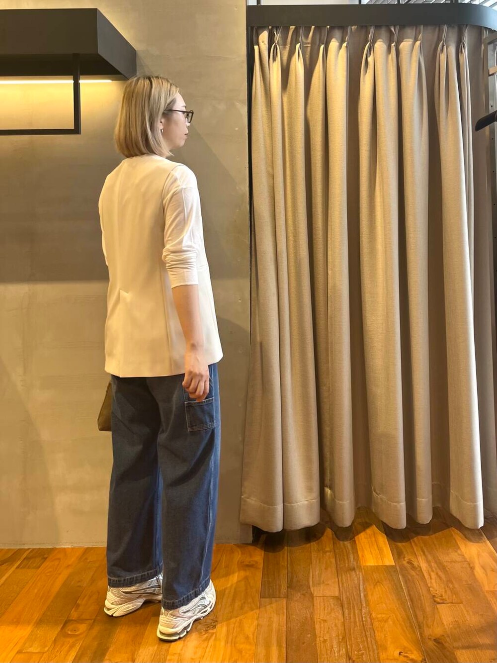 ブルー系のデニムパンツ、ホワイト系のベストを着用したレディースの秋コーディネートの2枚目の写真