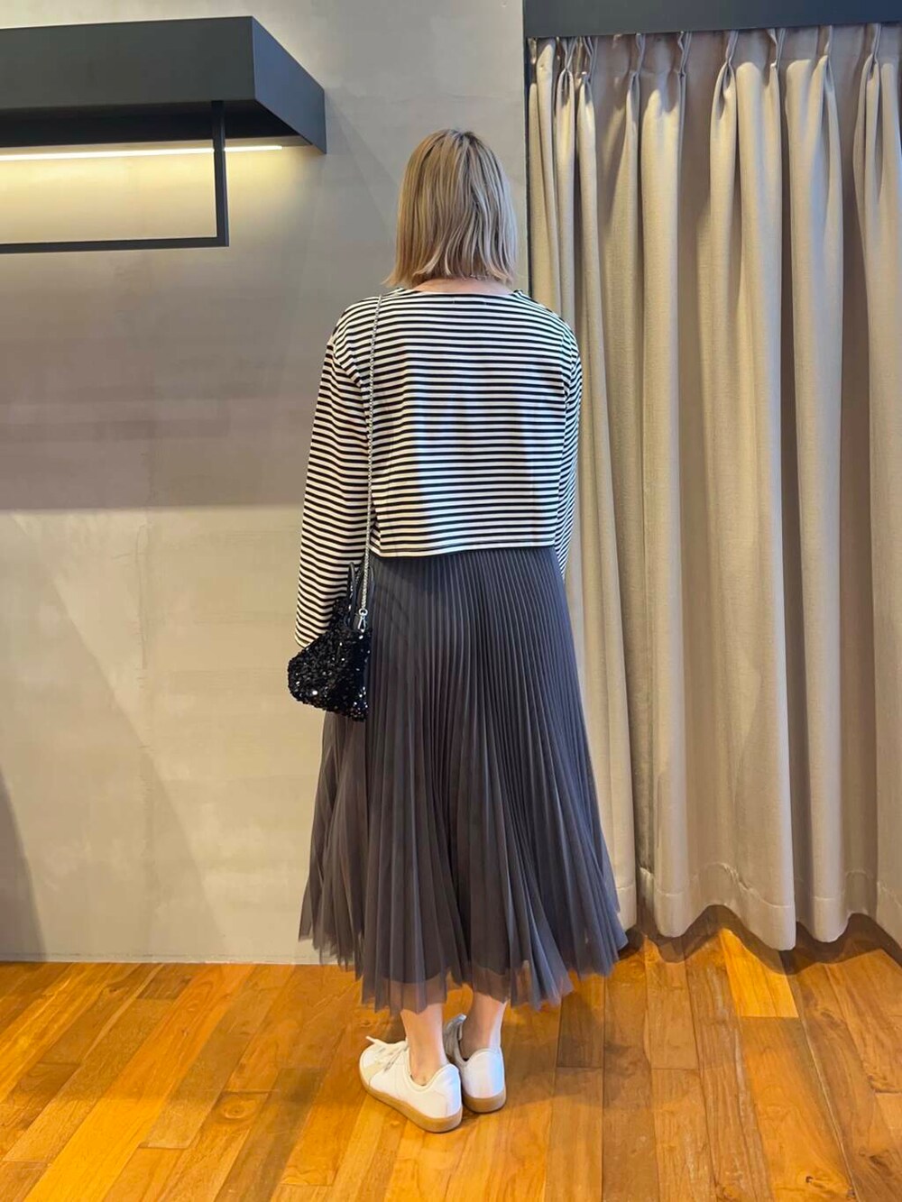 ブラック系のショルダーバッグ、グレー系のスカート、ホワイト系のTシャツ/カットソーを着用したレディースの夏コーディネートの2枚目の写真