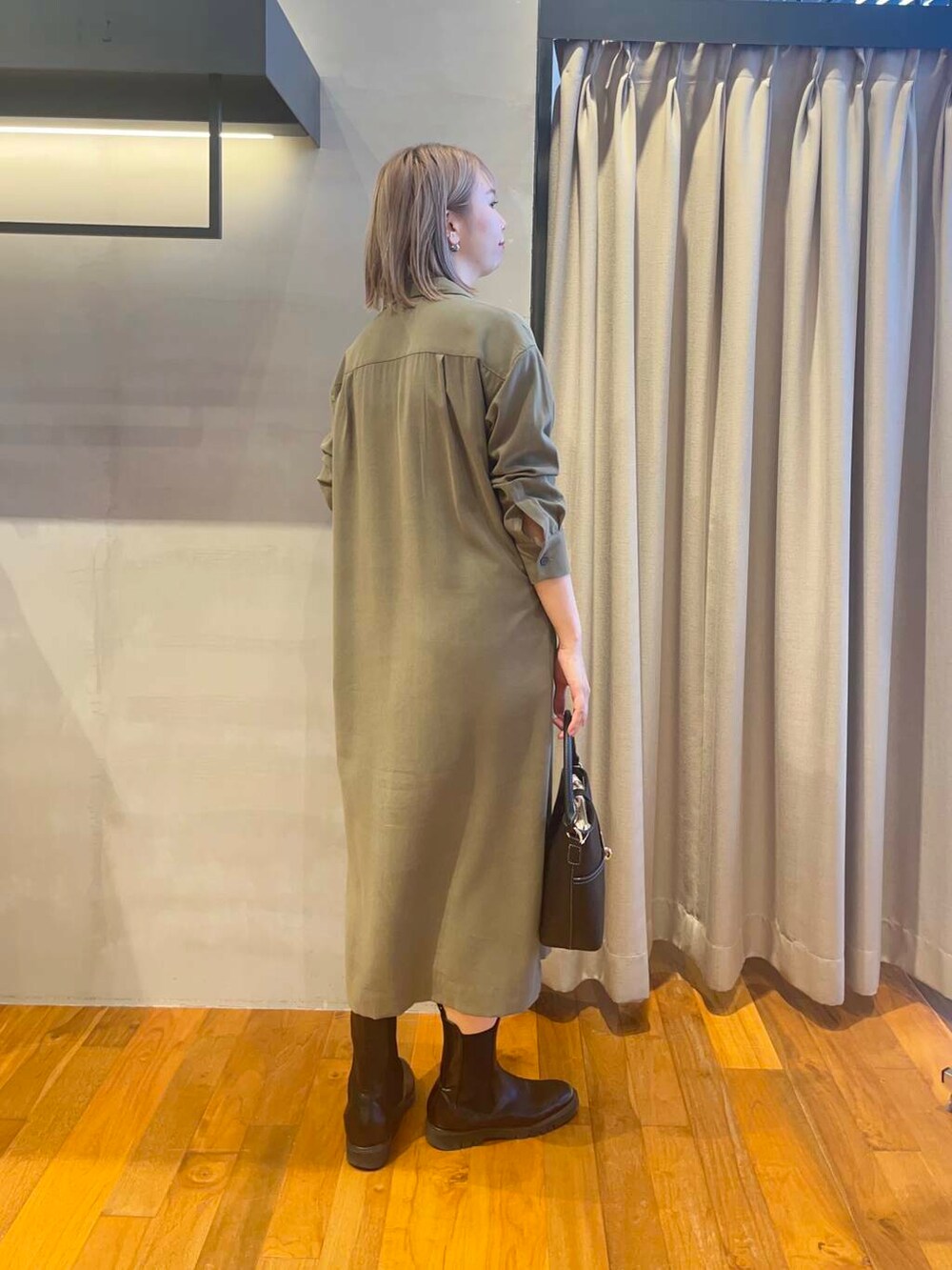 ブラック系のハンドバッグ、グリーン系のワンピース、ゴールド系のネックレスを着用したレディースの秋コーディネートの3枚目の写真