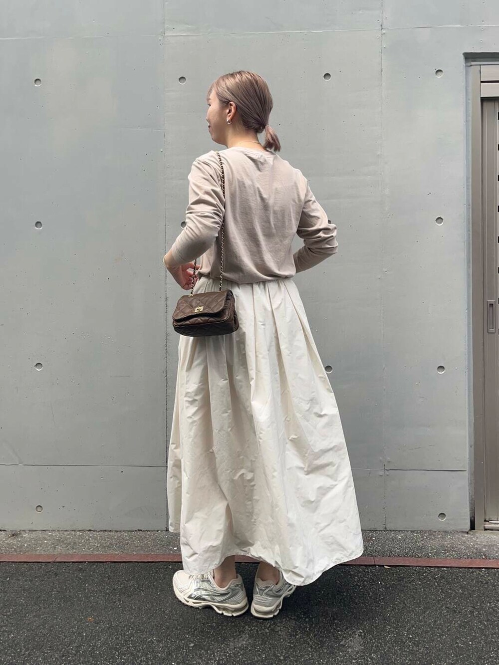 ブラウン系のショルダーバッグ、ホワイト系のスカート、ベージュ系のTシャツ/カットソーを着用したレディースの秋コーディネートの3枚目の写真