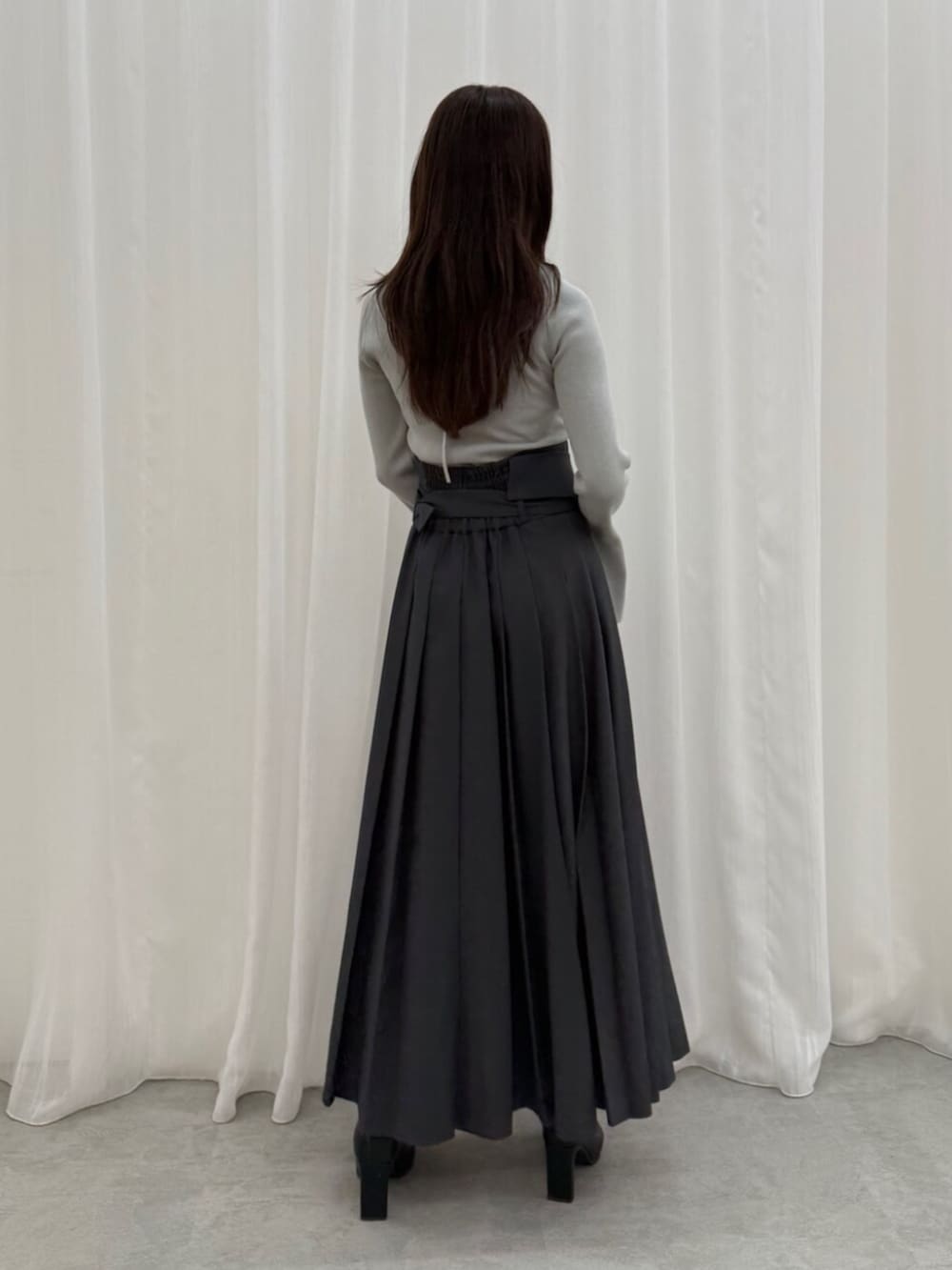 グレー系のスカート、グレー系のニット/セーター、ブラック系のブーツを着用したレディースの秋コーディネートの3枚目の写真