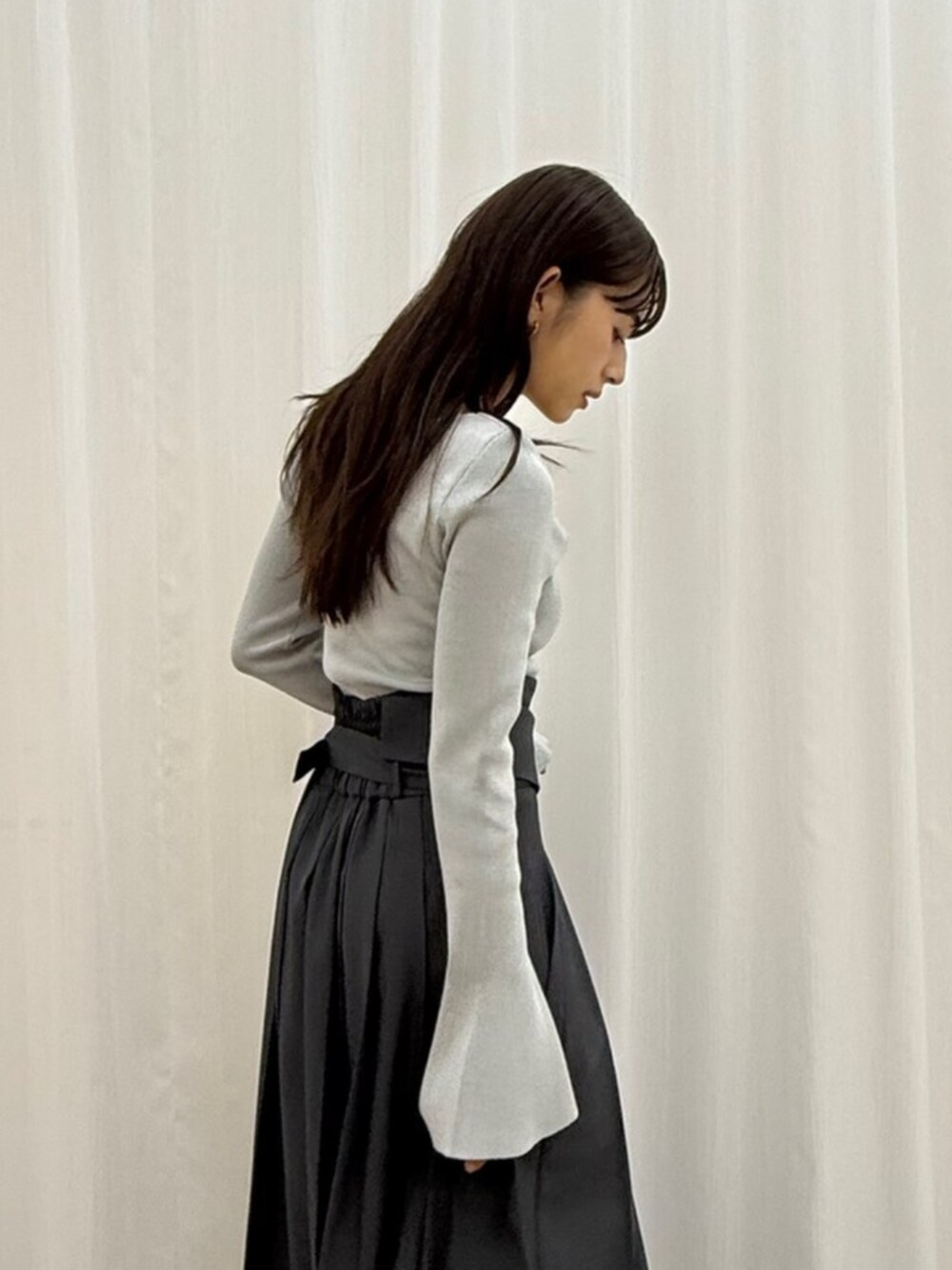 グレー系のスカート、グレー系のニット/セーター、ブラック系のブーツを着用したレディースの秋コーディネートの4枚目の写真