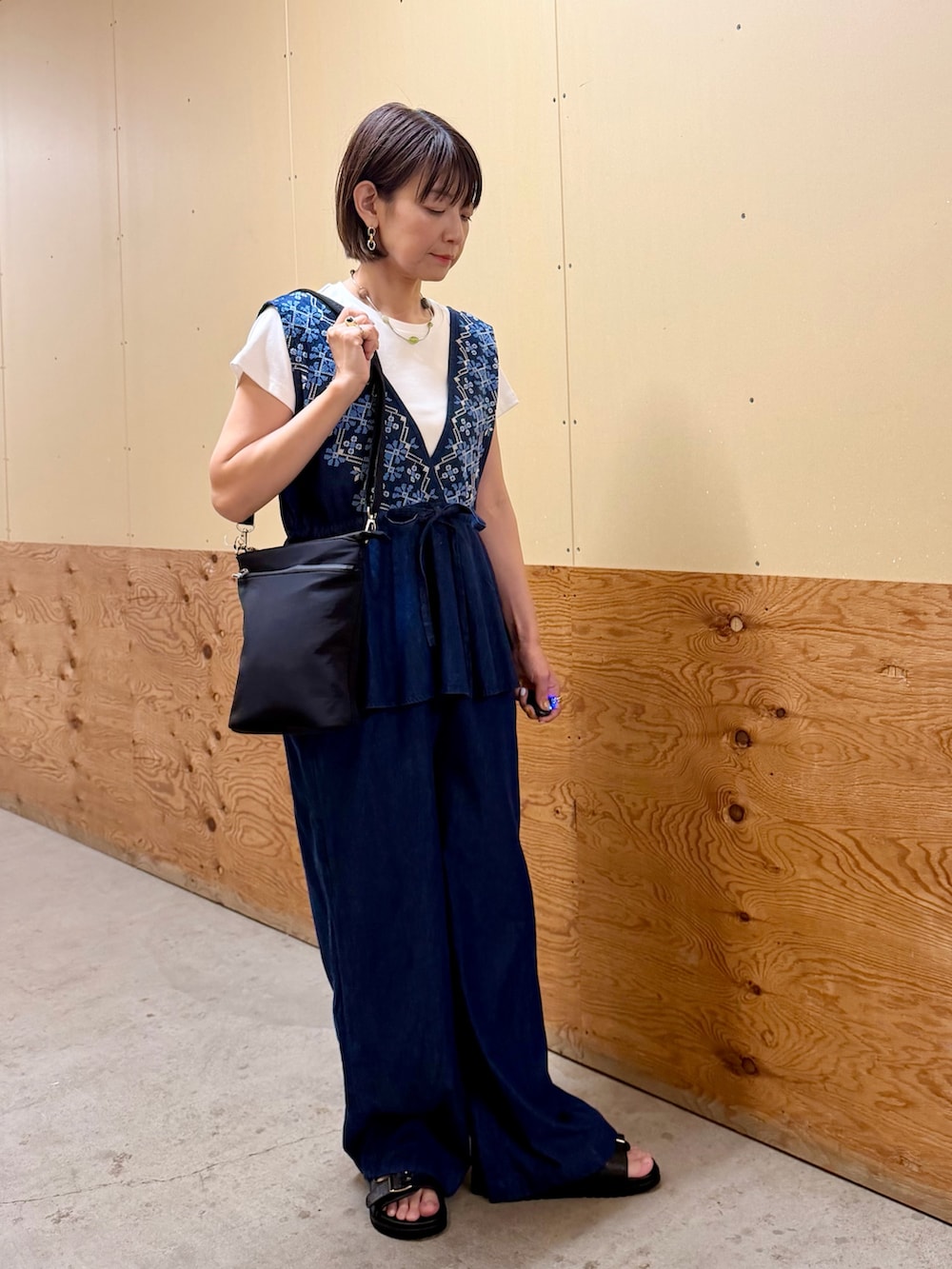 ブルー系のサロペット/オーバーオール、ホワイト系のTシャツ/カットソー、ブラック系のサンダルを着用したレディースの夏コーディネートの6枚目の写真