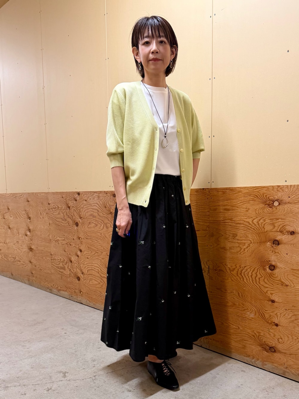 イエロー系のカーディガン/ボレロ、ブラック系のスカート、ホワイト系のTシャツ/カットソーを着用したレディースの春コーディネートの5枚目の写真