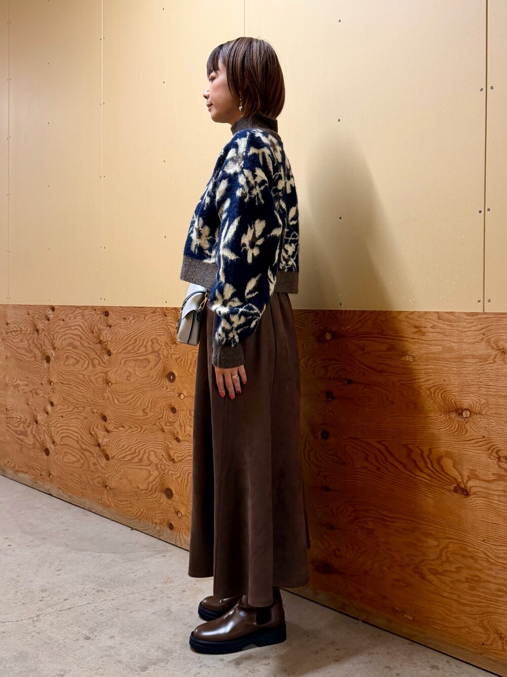 ブルー系のニット/セーター、グレー系のスカート、シルバー系のショルダーバッグを着用したレディースの秋コーディネートの3枚目の写真