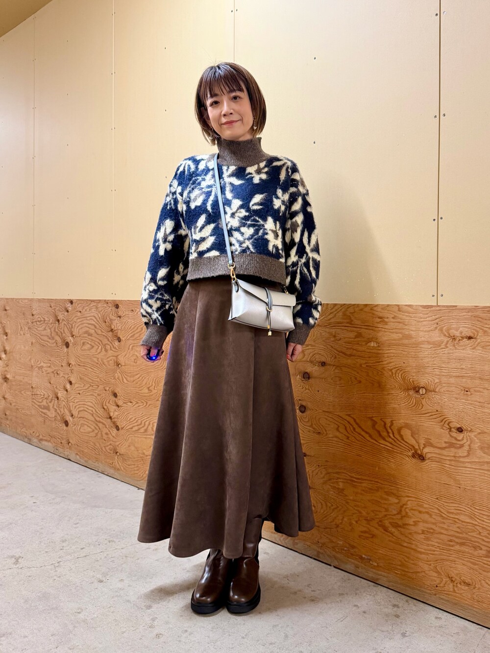 ブルー系のニット/セーター、グレー系のスカート、シルバー系のショルダーバッグを着用したレディースの秋コーディネートの2枚目の写真