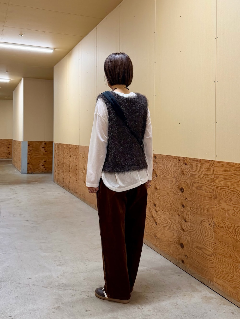 ホワイト系のTシャツ/カットソー、ブラウン系のベスト、ブラック系のショルダーバッグを着用したレディースの秋コーディネートの3枚目の写真