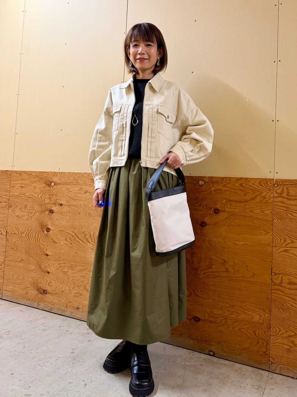 ホワイト系のブルゾン、ブラック系のシャツ/ブラウス、グリーン系のスカートを着用したレディースの冬コーディネートの2枚目の写真