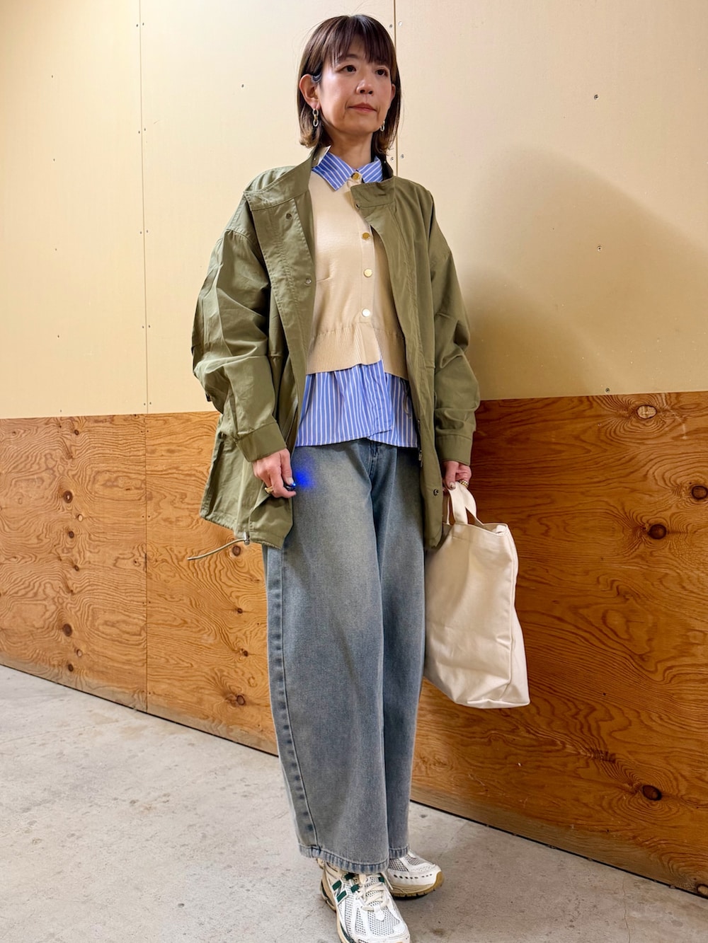 グリーン系のモッズコート、ホワイト系のニット/セーター、ブルー系のデニムパンツを着用したレディースの冬コーディネートの7枚目の写真