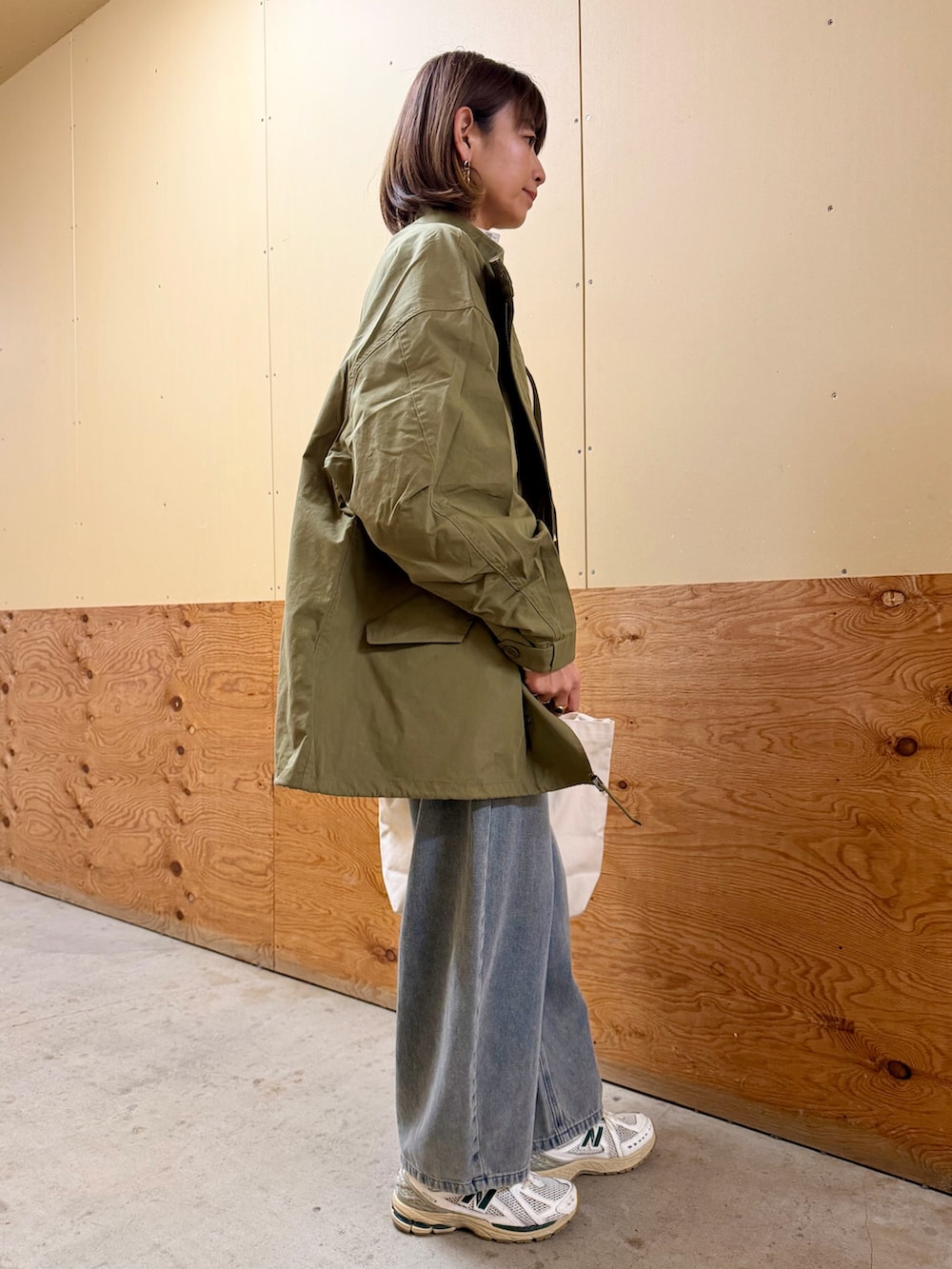 グリーン系のモッズコート、ホワイト系のニット/セーター、ブルー系のデニムパンツを着用したレディースの冬コーディネートの6枚目の写真