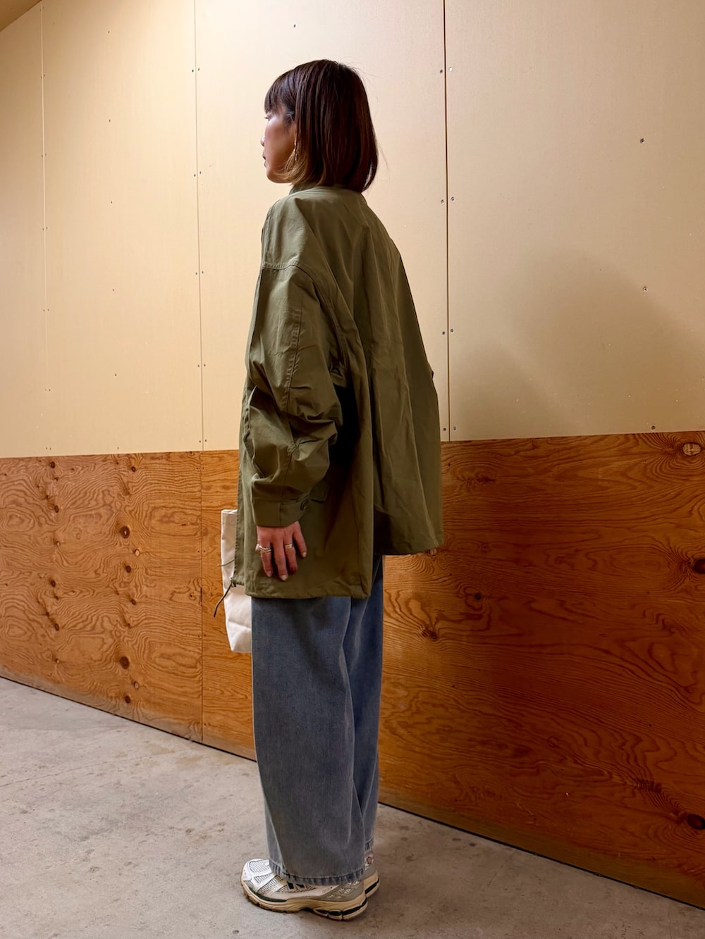 グリーン系のモッズコート、ホワイト系のニット/セーター、ブルー系のデニムパンツを着用したレディースの冬コーディネートの4枚目の写真