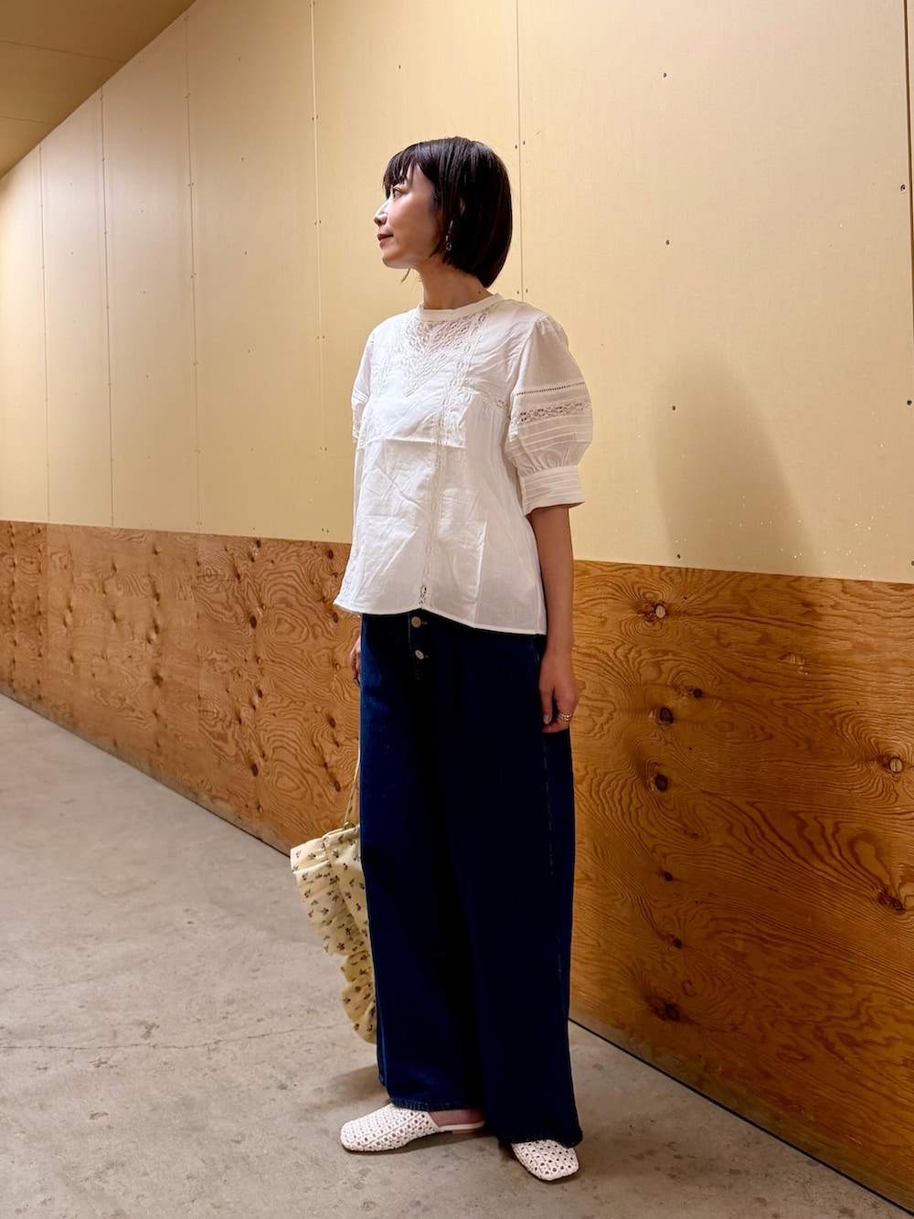 ブルー系のデニムパンツ、ホワイト系のトートバッグ、ホワイト系のサンダルを着用したレディースの夏コーディネートの2枚目の写真