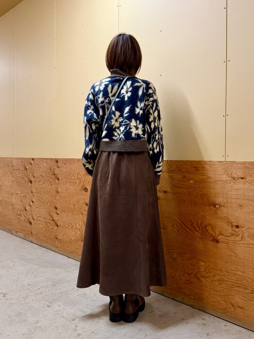 ブルー系のニット/セーター、グレー系のスカート、シルバー系のショルダーバッグを着用したレディースの秋コーディネートの4枚目の写真