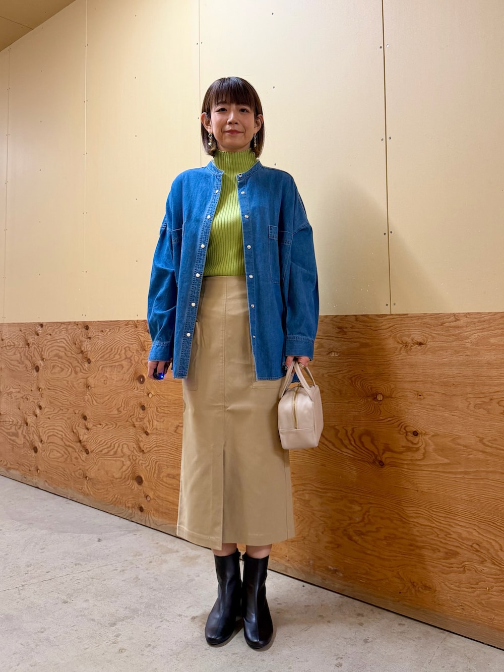 ブルー系のシャツ/ブラウス、グリーン系のニット/セーター、ベージュ系のスカートを着用したレディースの冬コーディネートの2枚目の写真