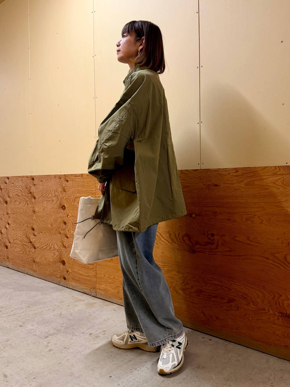 グリーン系のモッズコート、ホワイト系のニット/セーター、ブルー系のデニムパンツを着用したレディースの冬コーディネートの3枚目の写真