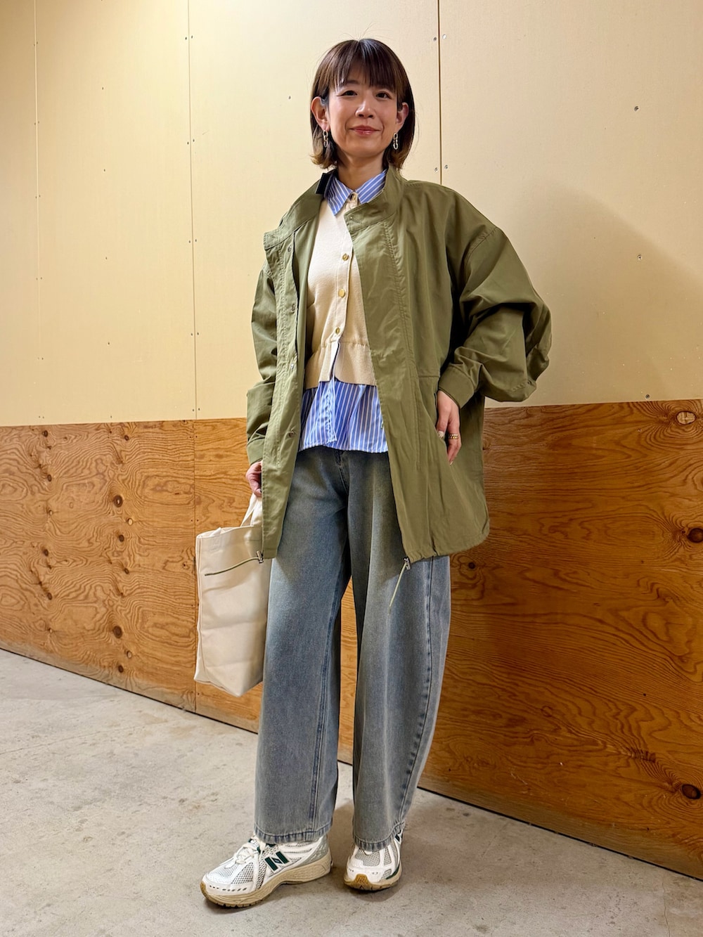 グリーン系のモッズコート、ホワイト系のニット/セーター、ブルー系のデニムパンツを着用したレディースの冬コーディネートの2枚目の写真