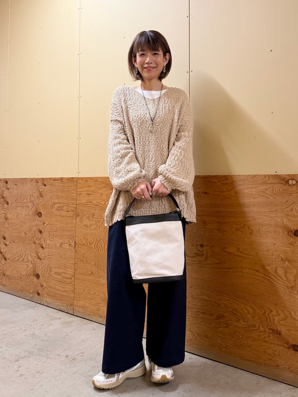 ベージュ系のニット/セーター、ブルー系のその他パンツ、ブラック系のショルダーバッグを着用したレディースの春コーディネートの2枚目の写真