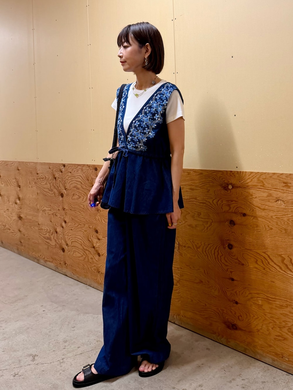 ブルー系のサロペット/オーバーオール、ホワイト系のTシャツ/カットソー、ブラック系のサンダルを着用したレディースの夏コーディネートの2枚目の写真