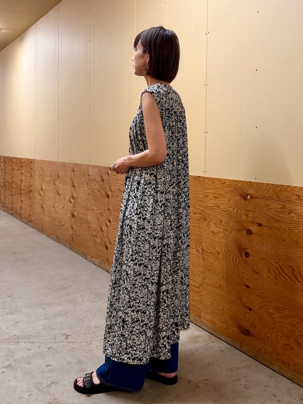 ブラック系のワンピース、ブルー系のデニムパンツ、ブラック系のサンダルを着用したレディースの夏コーディネートの3枚目の写真