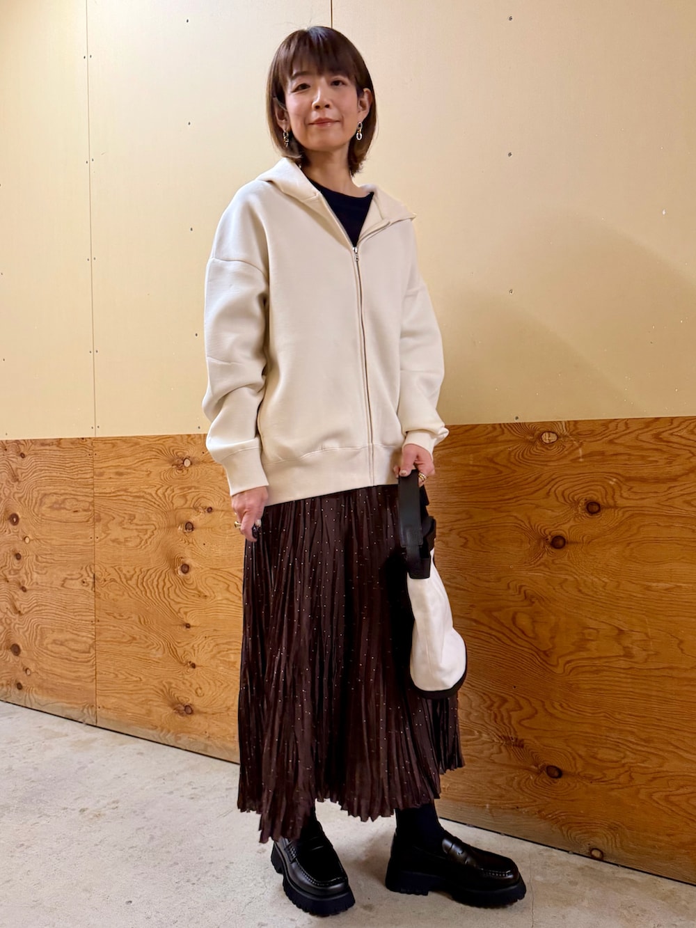 ホワイト系のパーカー、ブルー系のニット/セーター、ブラウン系のスカートを着用したレディースの春コーディネートの6枚目の写真