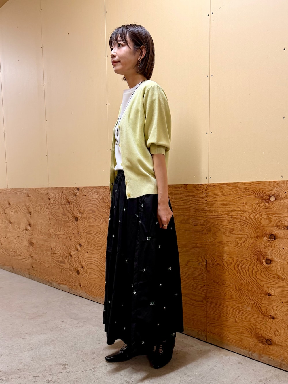 イエロー系のカーディガン/ボレロ、ブラック系のスカート、ホワイト系のTシャツ/カットソーを着用したレディースの春コーディネートの2枚目の写真