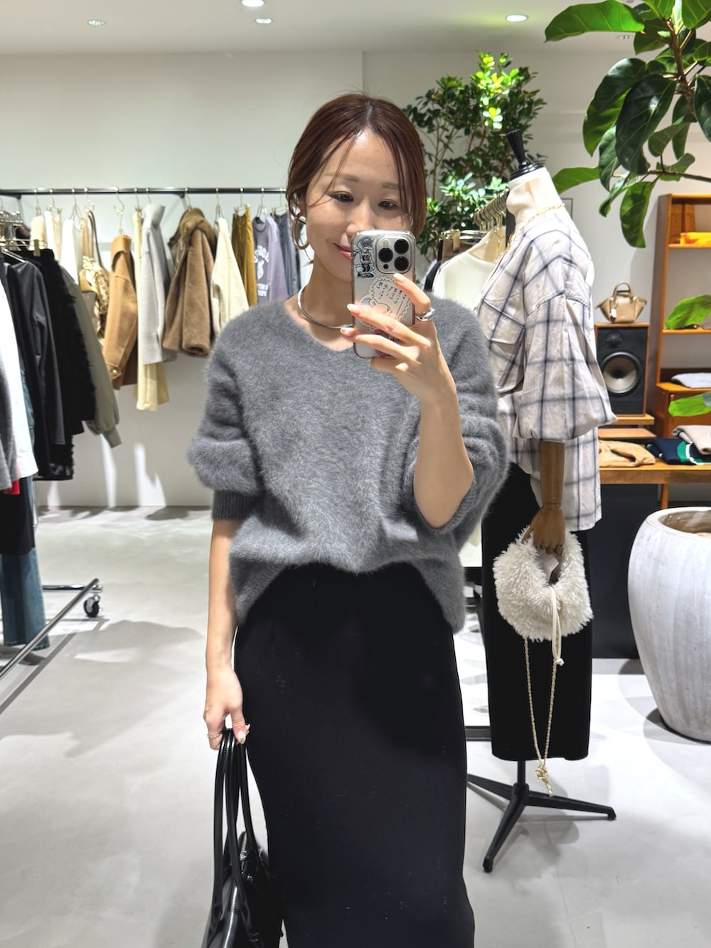 グレー系のニット/セーター、ブラック系のスカート、ブラック系のボストンバッグを着用したレディースの秋コーディネートの2枚目の写真