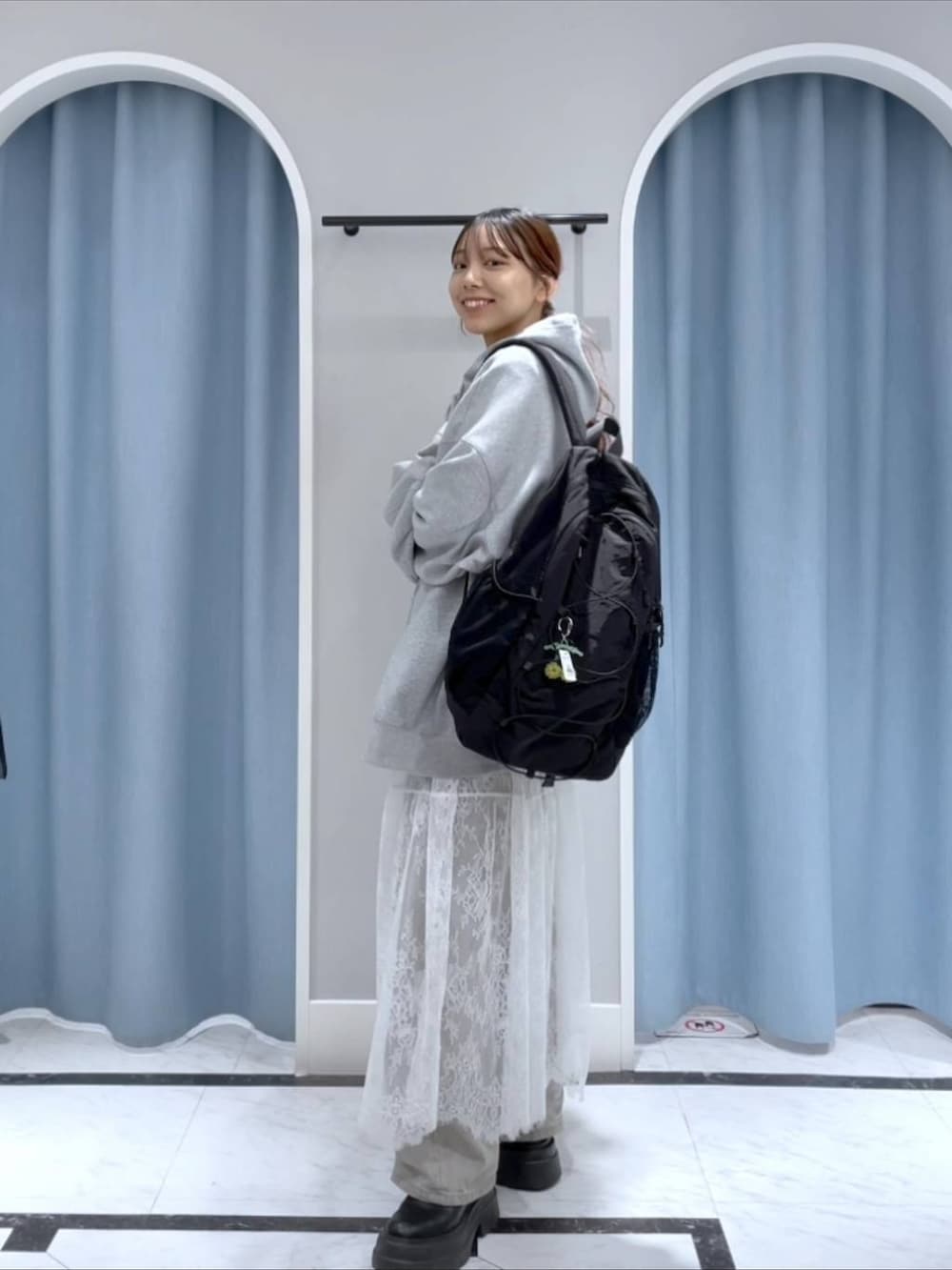 グレー系のデニムパンツ、ブラック系のバックパック/リュック、ホワイト系のスカートを着用したレディースの春コーディネートの2枚目の写真