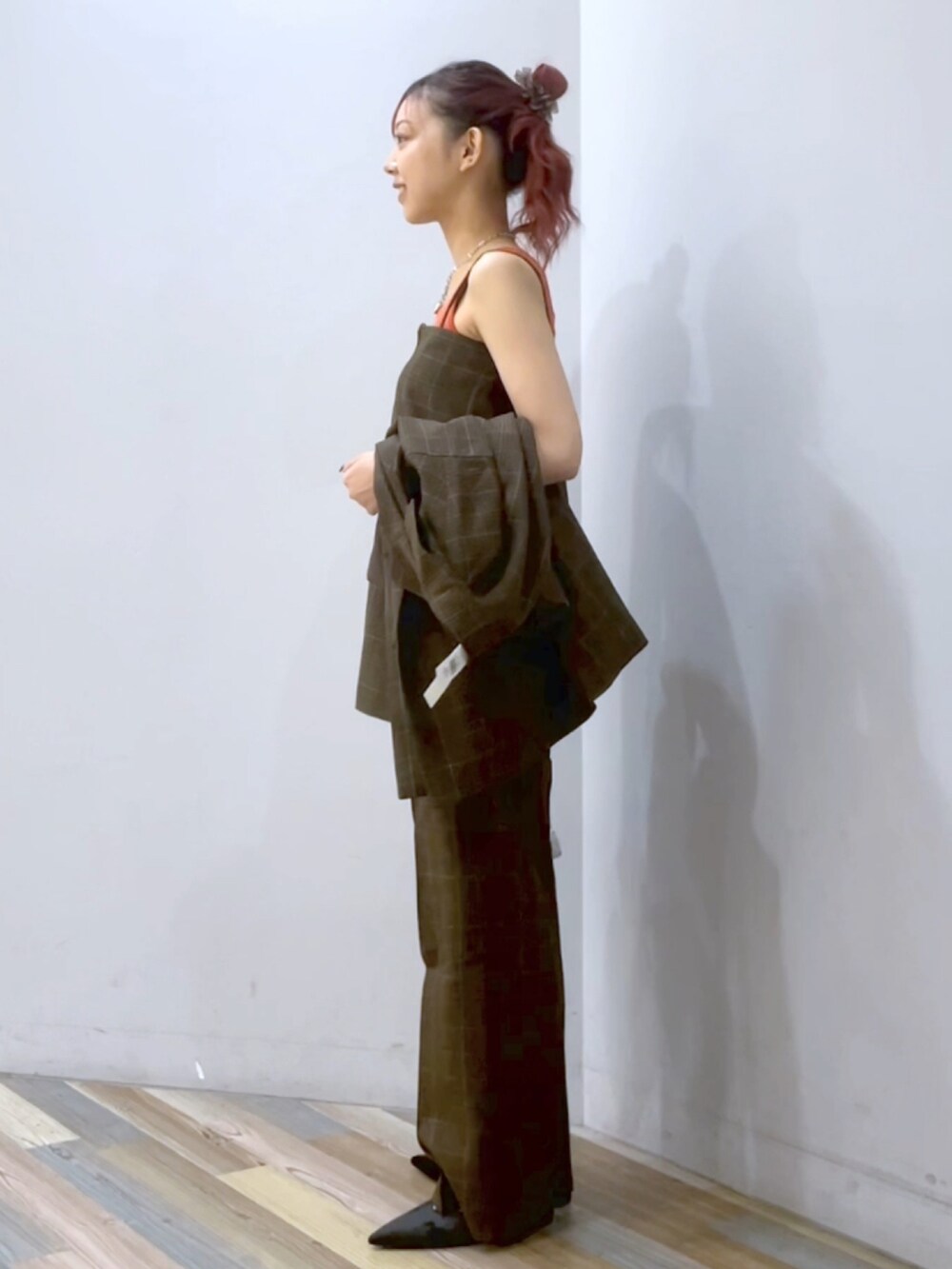 ブラウン系のスラックス、ブラック系のパンプス、シルバー系のショルダーバッグを着用したレディースの秋コーディネートの2枚目の写真