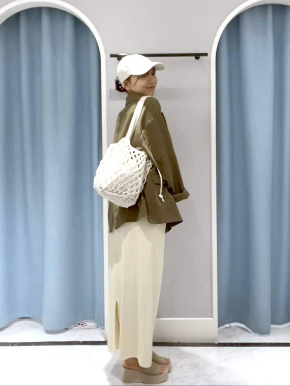 ホワイト系のスカート、グリーン系のテーラードジャケット、ホワイト系のサンダルを着用したレディースの春コーディネートの2枚目の写真