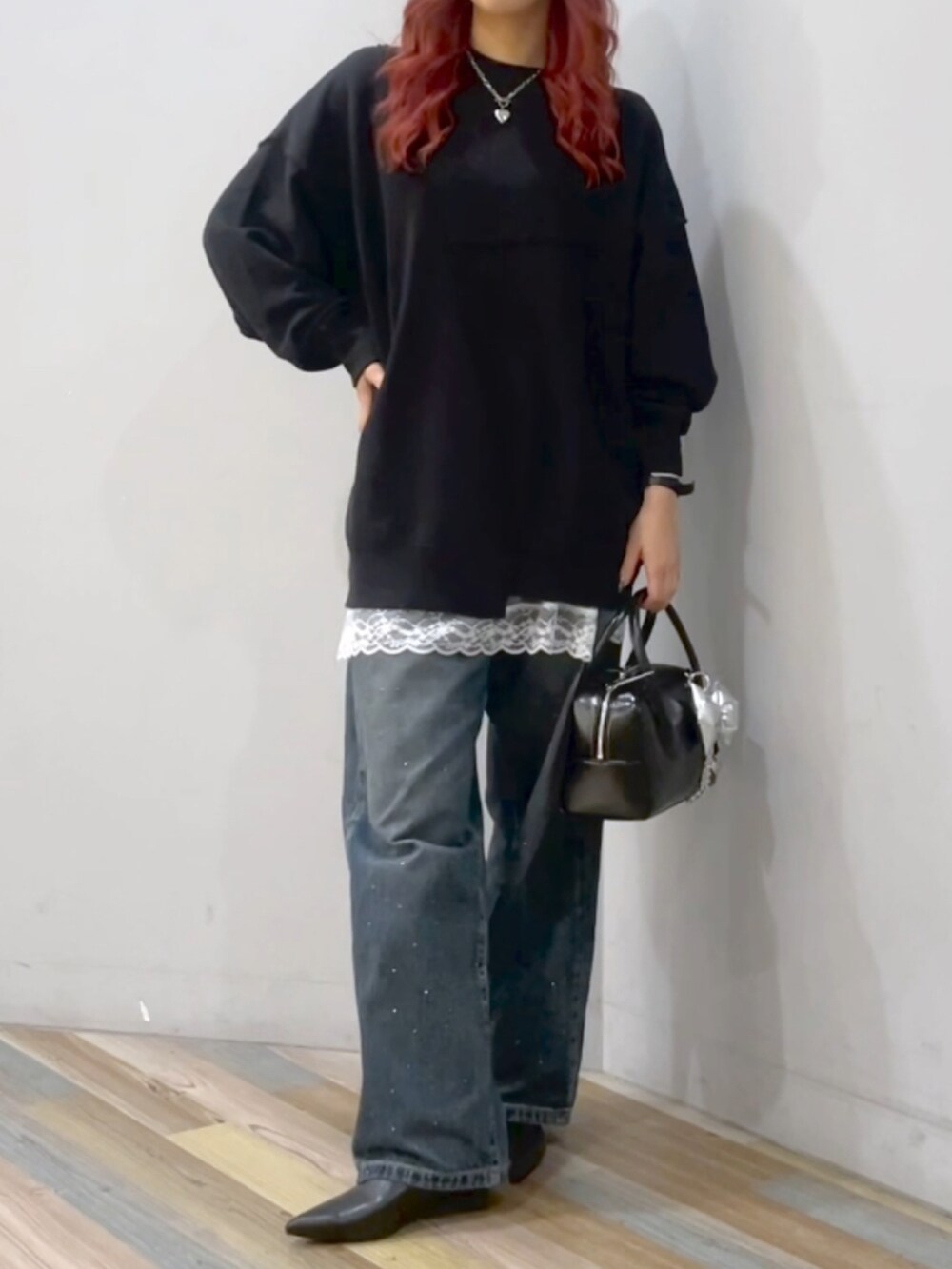 ブラック系のボストンバッグ、ブルー系のデニムパンツ、ブラック系のブーツを着用したレディースの秋コーディネートの2枚目の写真