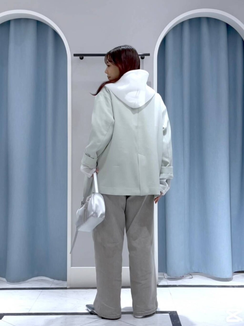 グリーン系のテーラードジャケット、シルバー系のトートバッグ、グレー系のデニムパンツを着用したレディースの春コーディネートの3枚目の写真