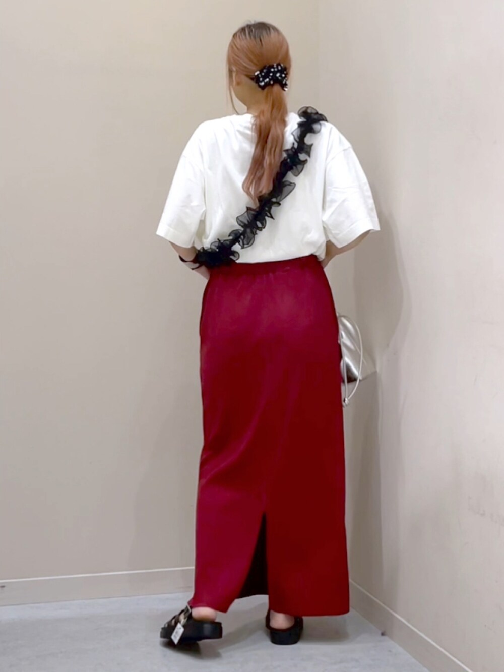 レッド系のスカート、ブラック系のスニーカーを着用したレディースの秋コーディネートの2枚目の写真