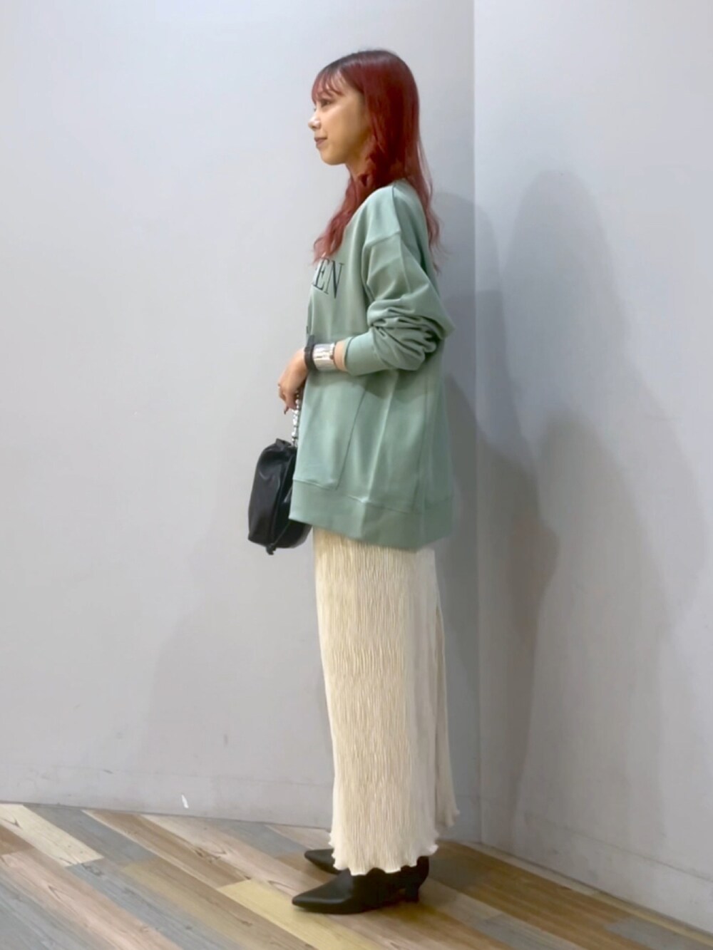 ブラック系のショルダーバッグ、ホワイト系のスカート、ブラック系のブーツを着用したレディースの秋コーディネートの2枚目の写真