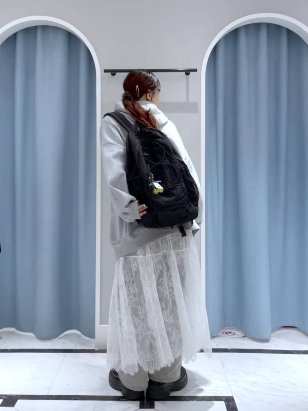 グレー系のデニムパンツ、ブラック系のバックパック/リュック、ホワイト系のスカートを着用したレディースの春コーディネートの3枚目の写真